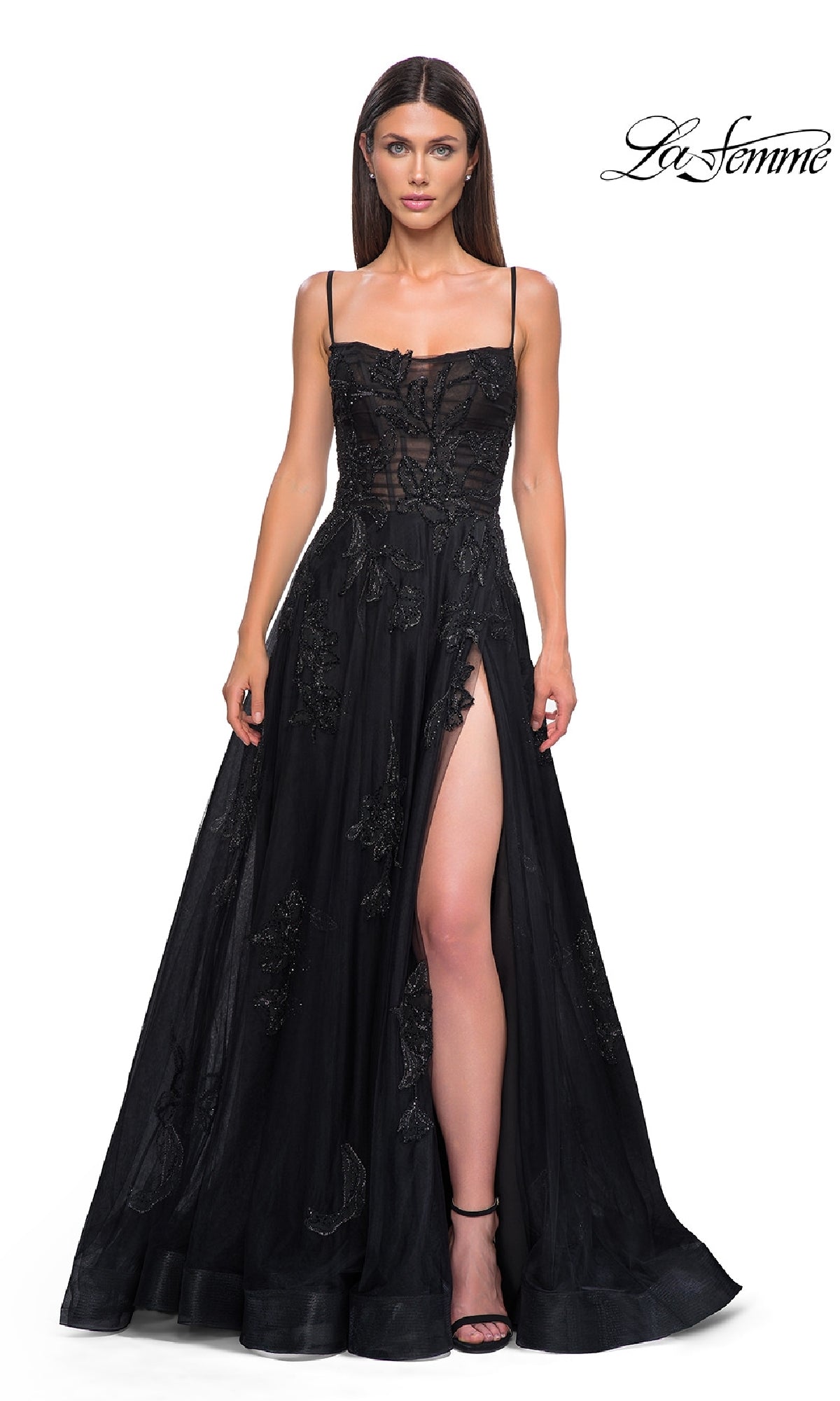 A woman poses against a white background in the Long Black Glitter Prom Dress, La Femme 32781—an elegant sleeveless gown with a sheer bodice, floral details, and high slit.